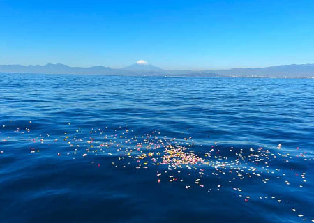 富士山を望む海に花を手向ける海洋散骨の光景